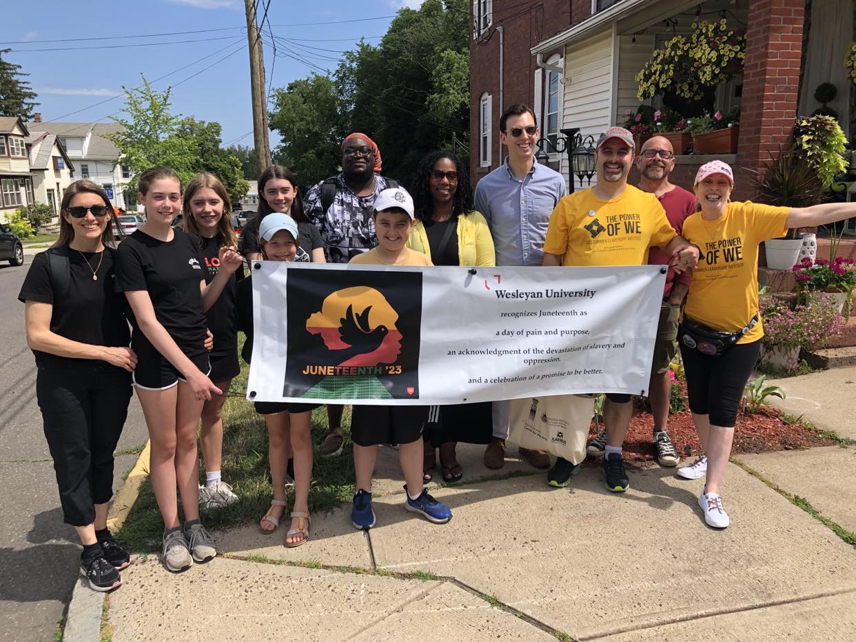 Wesleyan community members prepare to walk in the inaugural Juneteenth Parade on Rome Street in Middletown, including Marie McKenna, Administrative Assistant at the Allbritton Center for the Study of Public Life; Demetrius Colvin, Director of the Resource Center, Adjunct Instructor of Education Studies, and member of the Wesleyan Planning Committee for Juneteenth; Kai Belton, State Representative; Ben Florsheim ’14, Mayor, City of Middletown; Andrew Chatfield MALS ’19, Director of Arts Communication; and family members. (Andrew Chatfield MALS ’19)