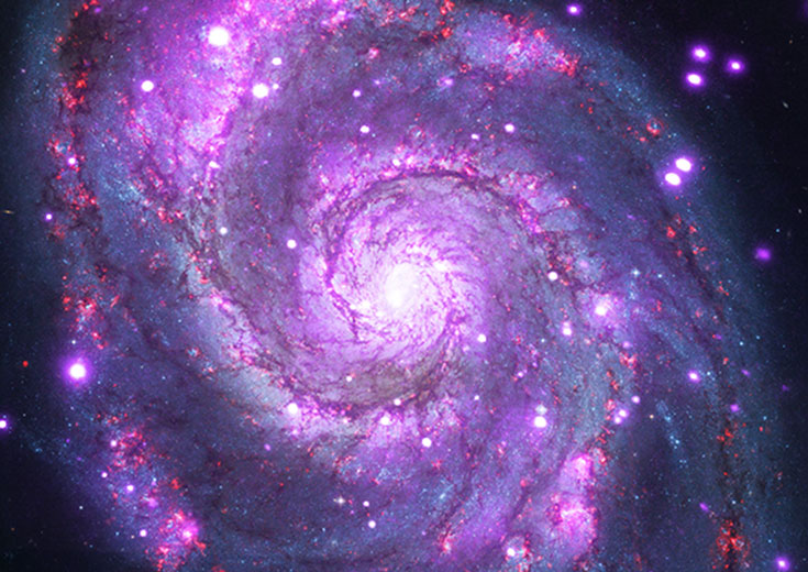 A spiral galaxy glitters with hundreds of X-ray points of light.