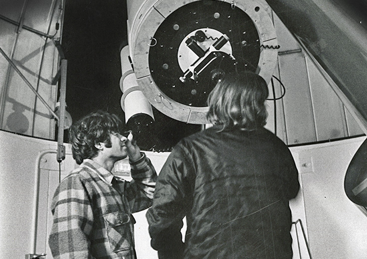 Two students observe a large telescope in a black-and-white photo from Wesleyan’s astronomy archives.